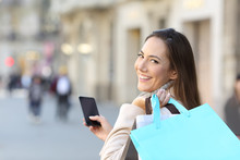 Happy Shopper Holding Phone And Shopping Bags