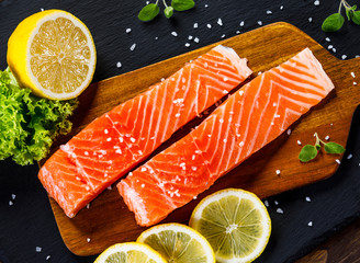 Fresh raw salmon fish served on black stone on wooden table