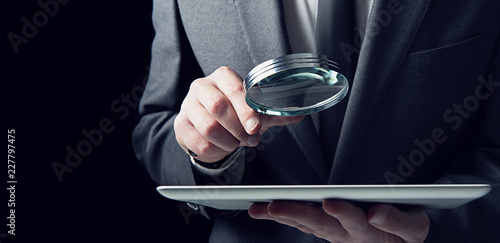 Fotografía Businessman examines a tablet with a magnifying glass