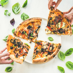 Wall Mural - Summer dinner or lunch. Flat-lay of people's hands taking freshly baked Italian vegetarian pizza with vegetables and fresh basil over white marble table, top view, square crop