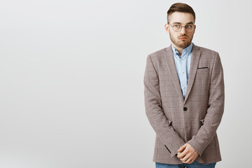 Wall Mural - Intense worried european male employee feeling awkward and confused making mistake being scolded by boss feeling discomfort being in uncomfortable situation holding hands near pants and gazing aside