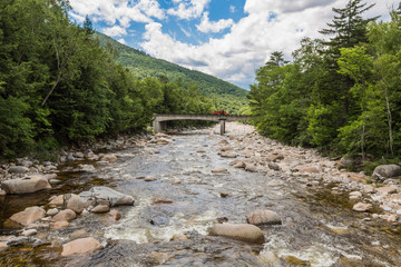 River through forest near the White Mountains  New Hampshire, a bridge in background