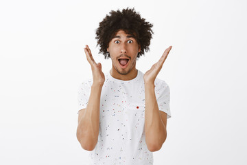 Wall Mural - Man describing feelings to friends after amazing match he attended. Portrait of impressed and amazed good-looking hispanic male with moustache and curly hair, gesturing palms and dropping jaw