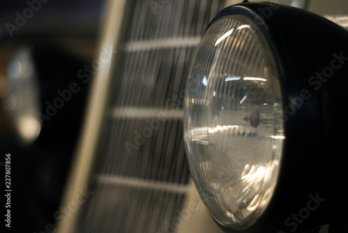 Fényképezés  headlight of a retro car close up, in the background a blurred grille