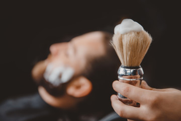 Wall Mural - Brush for shaving beard along with bowl, blurred background of hair salon men, barber shop