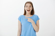 © Cookie Studio - Positive amazed attractive woman with fair hair in blue t-shirt, pointing left with forefinger, directing at awesome thing, smiling broadly, fascinated and joyful, standing stunned over grey wall
