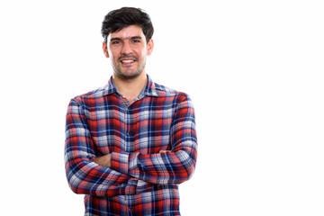 Studio shot of young happy Persian man smiling with arms crossed