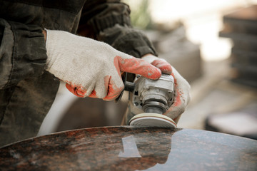 close-up a man in gloves polishes a marble monument with an angle grinder. man with a tool. worker m