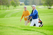 © pressmaster - Two aged buddies having talk while hurrying for game of golf along green field