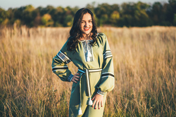 Pretty young brunette girl in long embroidery dress outdoor