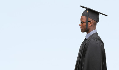 Sticker - Young graduated african american man over isolated background looking to side, relax profile pose with natural face with confident smile.