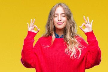 Poster - Beautiful young blonde woman wearing winter sweater over isolated background relax and smiling with eyes closed doing meditation gesture with fingers. Yoga concept.