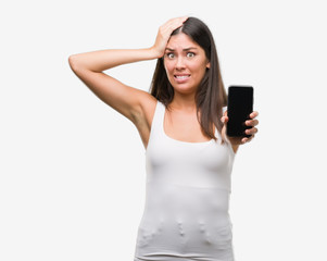 Sticker - Young beautiful hispanic showing smartphone stressed with hand on head, shocked with shame and surprise face, angry and frustrated. Fear and upset for mistake.