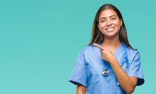 Young Arab Doctor Surgeon Woman Over Isolated Background Cheerful With A Smile Of Face Pointing With Hand And Finger Up To The Side With Happy And Natural Expression On Face Looking At The Camera.