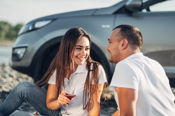 Wall Mural - Happy Traveler Couple on Picnic into the Sunset with SUV Car