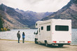 RV motorhome camper van road trip young people on New Zealand travel vacation adventure, Two tourists looking at lake and mountains on pit stop next to their rental car.