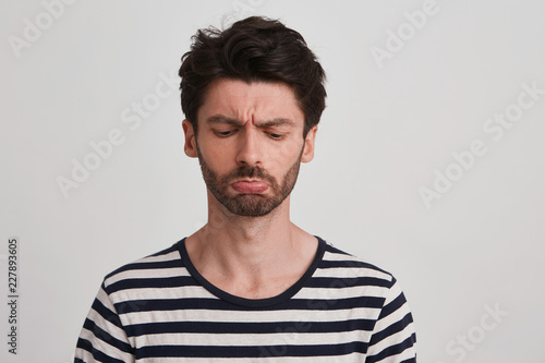 Studio Shot Of Young Brown Hair Man With Beard Looks Sadly Down