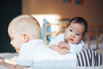 Cute little baby with elder brother lying on bed at home