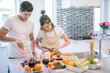 © saksit - young asian couple cooking together in the kitchen at home.