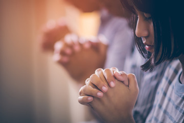 Asian Christian groups sitting within the Church Catholic. They clasped hands and closed his eyes and prayed for blessings from God. A pale sun shone in a place of worship. Everyone smiled happily.