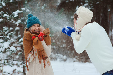 happy young couple playing on winter walk, throwing snowballs and having fun outdoor in snowy forest. Active winter vacation concept.