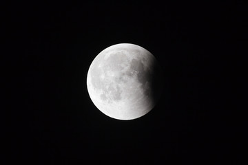 Wall Mural - super bloody moon, full eclipse last phase against black sky background, small part of moon surface 