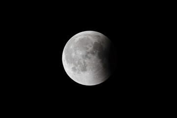 Wall Mural - super bloody moon, full eclipse last phase against black sky background, small part of moon surface 