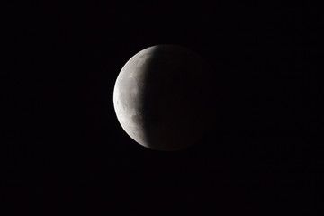 Wall Mural - super bloody moon, full eclipse end phase against black sky background, three-quarters of the moon s