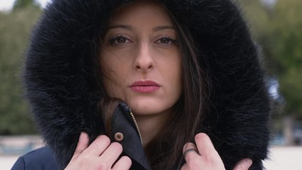 sad young woman with fur hood staring at camera.depression, loneliness- outdoor