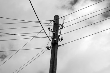 Old wooden electric pole against sky ijn black and white.