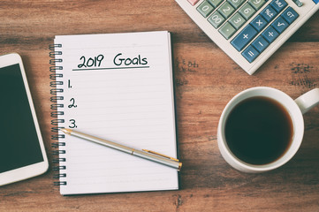 Wall Mural - New year Concept - 2019 goals text on notepad. Smartphone, pen and cup of copy background.
