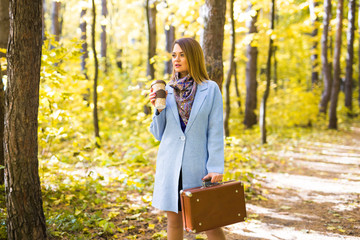 Autumn, nature and people concept - Young beautiful woman in blue coat holding a cup of coffee