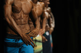 group athletes bodybuilders in colorful summer shorts at competitions in beach bodybuilding