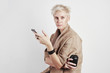 © olgapogorelova - Portrait of blond caucasian woman angry anxious emotion drinks takeaway coffee, using smartphone on white background.