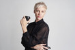 © olgapogorelova - Portrait of blond woman with short hair wearing black shirt drinks takeaway coffee, using smartphone on white background..