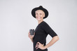 © olgapogorelova - Portrait of blond caucasian woman wearing black clothes and hat having disposable paper cup of coffee, posing on white background.