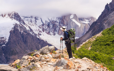 Cerro Torre, El Chaltén / Argentina - December 5 2016: Young man walking up to a view point and looking at immensity, with a backpack on, on a sunny day with mountains behind,near campsite De Agostini