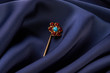 Gold hairpin with ruby precious stone on blue silk background with copy spce. Beautiful precious women's jewelry, close-up