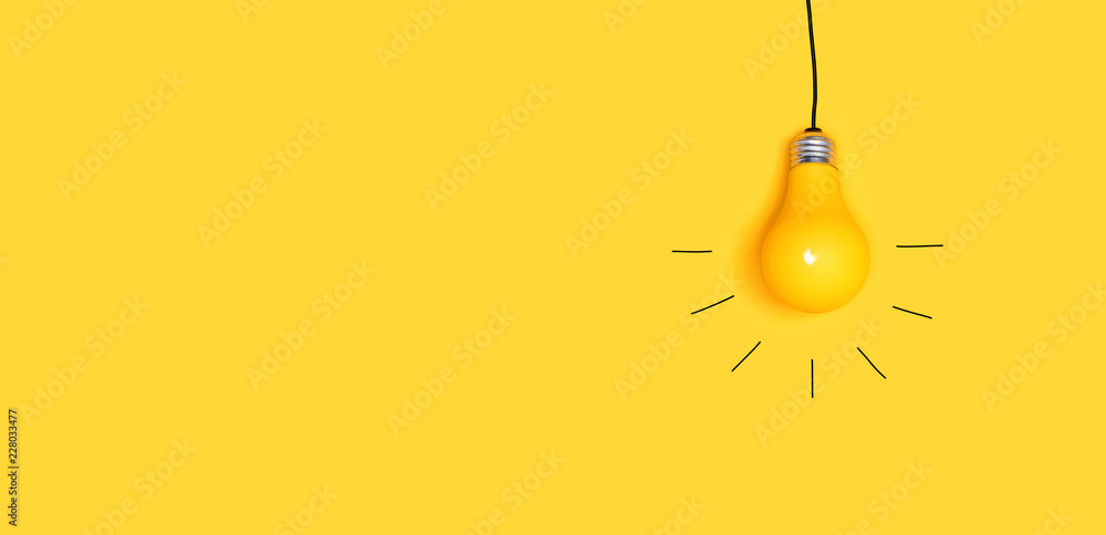 One hanging light bulb on a yellow background - obrazy, fototapety, plakaty 