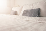 Fototapeta  - Bedding in bedroom with sunrise effect,clean white bedding sheet and pillows in beauty room interior