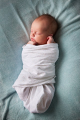 newborn baby sleeping peacefully, wrapped in blanket