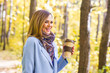 © satura_ - Autumn, drinks and people concept - Woman holding cup of hot drink