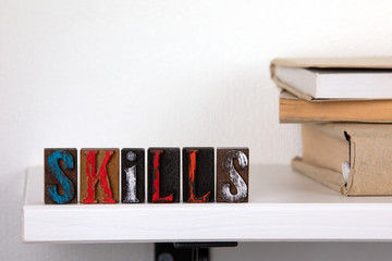 Wall Mural - skills - word from colored wooden letters un the whitte shelf near books