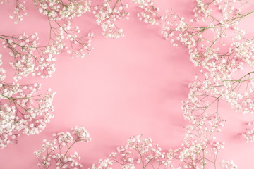 Wall Mural - frame made of small white flowers on pastel pink background. happy women's day, wedding, mother's da