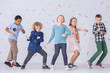 Girls and boys dancing together in the school. Happy friends against colorful wallpaper
