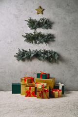 handmade christmas tree hanging on grey wall, gift boxes on carpet in room