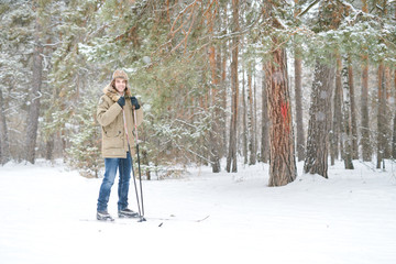 Wall Mural - Full length portrait of happy young man smiling at camera while enjoying skiing in snowy winter forest, copy space