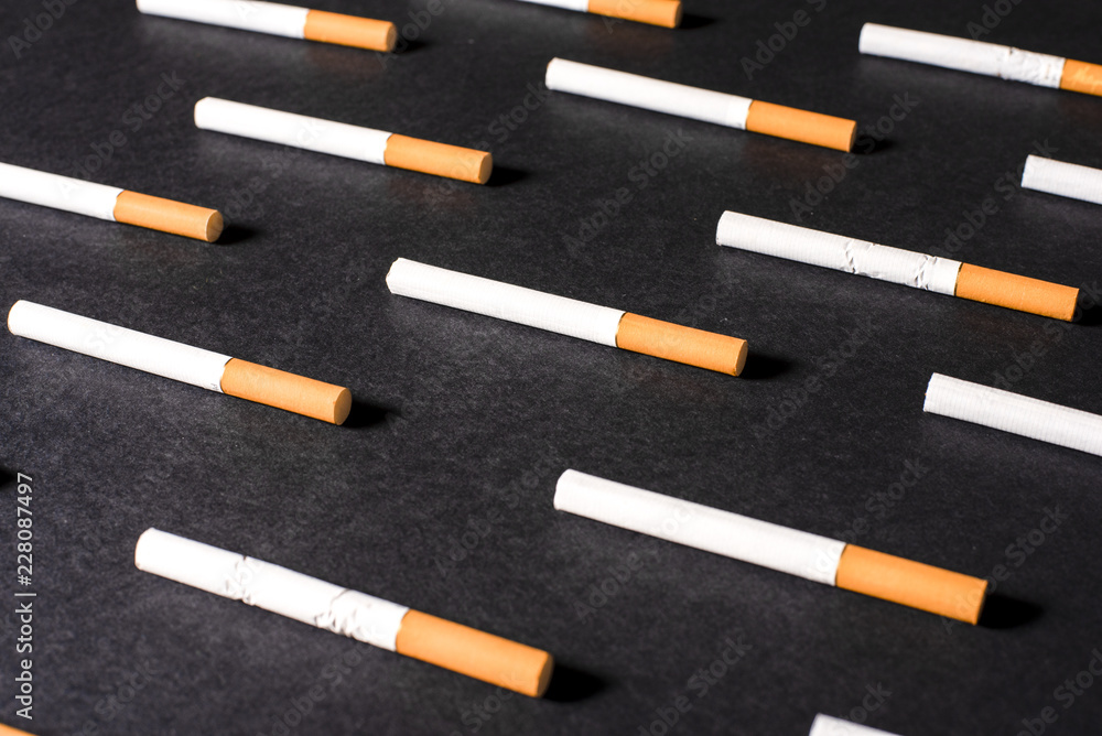 White cigarettes with orange filter lined in a row in order Stock Photo