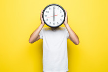 Young Man Holding Big Clock Covering His Face On Yellow Background