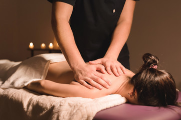 Wall Mural - Close up Male manual worker doing spa massage to a young girl in a dark room